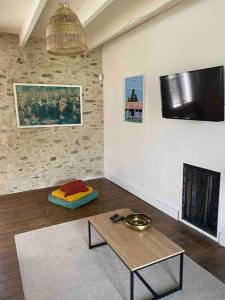 - un salon avec une table et une télévision murale dans l'établissement Gîte Belfortes plein cœur de Brassac, à Brassac
