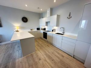 a kitchen with white cabinets and a wooden floor at Ocean View Suite - Near Hythe - On Beach Seafront - Private Parking in Dymchurch