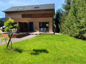 a house with a green lawn in front of it at Duplex le Corten, Terrasse et jardin in Gérardmer