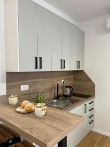 Eine Küche mit weißen Schränken und ein Tisch mit einem Teller Brot in der Unterkunft INFINITY Studioapartman, Self Check-in in Posušje