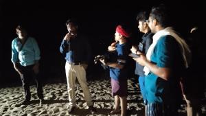 a man talking to a group of people in the dark at Jhoomke camping and water sports adventure in Auraiya