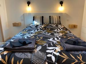 a bed with a comforter and towels on it at Duplex le Corten, Terrasse et jardin in Gérardmer