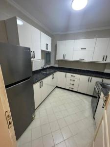 a kitchen with white cabinets and a black refrigerator at شقة في مدينتي بي 2 جديدة in Madinaty