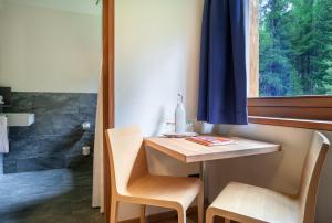 uma casa de banho com uma mesa, 2 cadeiras e uma janela em Gletscher-Hotel Morteratsch em Pontresina