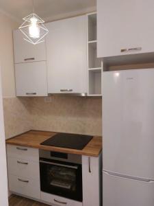 a kitchen with white cabinets and a refrigerator at Apartments Relax in Utjeha