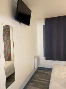 um quarto com uma cama e uma televisão na parede em FASTHOTEL A Dijon em Dijon