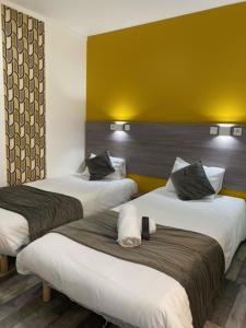 duas camas num quarto de hotel com paredes amarelas em FASTHOTEL A Dijon em Dijon