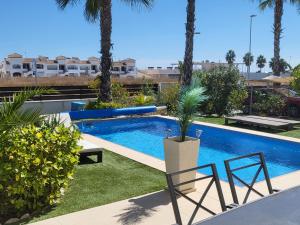 una piscina con 2 sillas y una palmera en Luxury Golf Villa in Vistabella Golf Costa Blanca, en Orihuela
