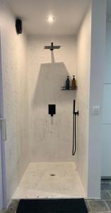 e bagno con doccia su una parete bianca. di Residentie Don a Bruges