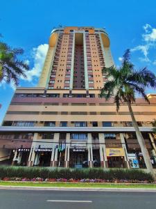 a tall building with a palm tree in front of it at Hotel Metrópole Maringá in Maringá