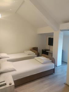 a bedroom with two beds and a desk and a television at UB Prenociste in Vranjska Banja