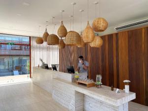 un homme se tient derrière un comptoir dans un hall dans l'établissement Flat Île de Pipa Premium - By Almare, à Pipa 29 autres photos