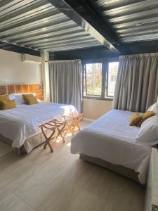 a bedroom with two beds and a table and windows at 718 Rufino Petit Hotel in Mendoza
