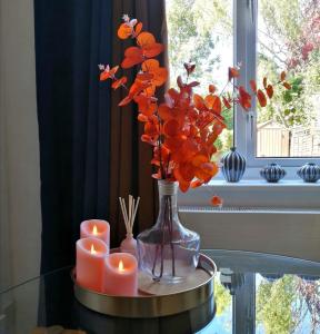 a vase with orange flowers and candles on a table at 2 Bedroom House in Quiet Area, Close to M5 With Free Parking by Glos Homes Ltd in Gloucester