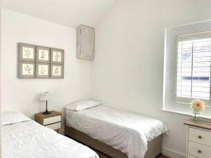 a white bedroom with two beds and a window at Converted Barn at Stonehouse Farm 