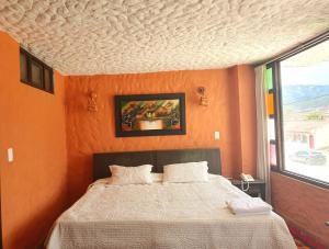 een slaapkamer met een bed met een oranje muur bij HOTEL COMPOSTELLA in Paipa