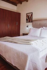 Schlafzimmer mit einem großen weißen Bett und Holzschränken in der Unterkunft The Charming Lemon Tree House in Maipú