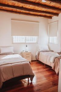 1 Schlafzimmer mit 2 Betten und Holzboden in der Unterkunft The Charming Lemon Tree House in Maipú