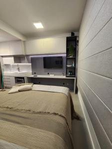 a bedroom with a bed and a flat screen tv at Aconchegante e moderno Studio! Ótima localização! in Curitiba