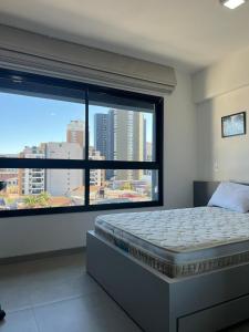 a bedroom with a bed and a large window at Aconchegante e moderno Studio! Ótima localização! in Curitiba