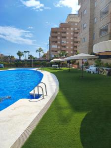 ein Pool mit grünem Gras neben einem Gebäude in der Unterkunft Magic World Apartamento Lyz y Mar in Oropesa del Mar