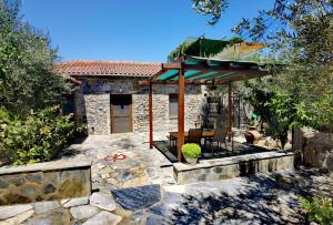 a stone house with a table and a pavilion at Elaion Thea-Nies in Soúrpi