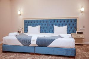 a large bed with a blue headboard in a room at al Madina Hotel Samarkand in Samarkand