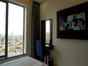 a bedroom with a large window with a tv on the wall at Violet Rose ApartHotel in Jeddah