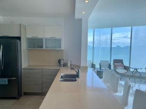 a kitchen with a sink and a counter with chairs at 17E Beautiful 2-Bedroom Ocean View Apartment in Playa Bonita Village