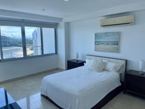 ein Schlafzimmer mit einem weißen Bett und einem großen Fenster in der Unterkunft 17E Beautiful 2-Bedroom Ocean View Apartment in Playa Bonita Village