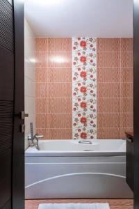 a bath tub in a bathroom with a floral wallpaper at Ionias Apartment in Heraklion in Heraklio