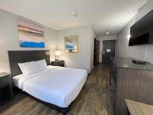 a hotel room with a white bed and a flat screen tv at Days Inn by Wyndham Orange Park/Jacksonville in Orange Park