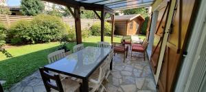 une terrasse couverte avec une table et des chaises. dans l'établissement Un Havre de Paix, à Villepinte