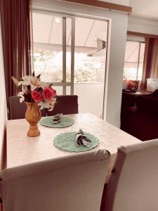 維多利亞的住宿－APTO - Espaço Village Completo - 2Q，一张桌子,上面有两盘盘,花瓶