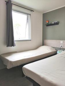 um quarto com duas camas e uma janela em Mobil Home Le Rimbaud - 4/6 pers - 2 ch - 2 sdb em Saint-Jean-de-Monts