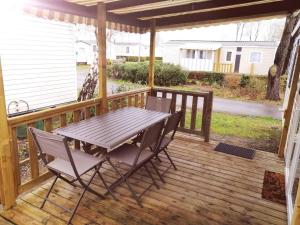 a wooden deck with a table and chairs on it at Mobil Home Le Rimbaud - 4/6 pers - 2 ch - 2 sdb in Saint-Jean-de-Monts