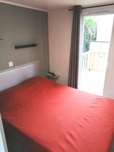 a bedroom with a red bed and a large window at Mobil Home Le Rimbaud - 4/6 pers - 2 ch - 2 sdb in Saint-Jean-de-Monts