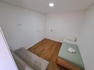 um pequeno quarto com uma cama e um sofá em Beach House em Espinho