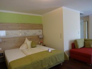 a bedroom with a bed and a red chair at AKZENT Hotel Landgasthof Murrer in Straubing