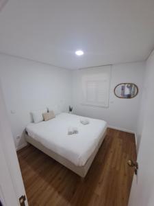 een wit bed in een kamer met een houten vloer bij Beach House 2 in Espinho