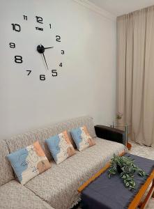 ein Wohnzimmer mit einem Sofa und einer Uhr an der Wand in der Unterkunft Apartment Alex in Athen