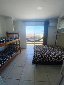 a bedroom with two bunk beds and a door to a balcony at Sobrados Molhes in Passo de Torres