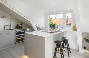 a white kitchen with a counter and stools at Erling Skjalgssons gate 32a in Oslo