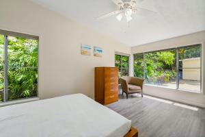 a bedroom with a bed and a chair and windows at @ Marbella Lane - Sunshine Seascape Ocean View in Kaneohe