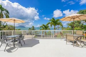 a patio with tables and umbrellas and the ocean at @ Marbella Lane - Sunshine Seascape Ocean View in Kaneohe
