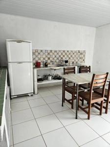 een keuken met een tafel en een koelkast bij Aconchegante casa perto da praia da Enseada dos Golfinhos OBS não é Jaguaribe in Jaguaribe