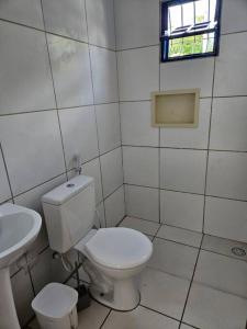 Baño blanco con aseo y lavamanos en Aconchegante casa perto da praia da Enseada dos Golfinhos OBS não é Jaguaribe en Jaguaribe