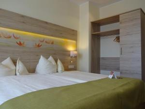 a bedroom with a large white bed with a wooden headboard at AKZENT Hotel Landgasthof Murrer in Straubing