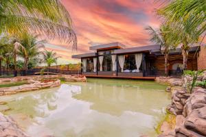 een huis met een vijver voor een resort bij Carpe Diem Eco Resort & SPA in Olímpia