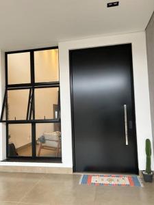 - une porte noire dans une chambre avec fenêtre dans l'établissement Casa com piscina e área gourmet com churrasqueira integrada, à Maringá